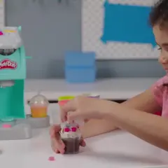 Dziewczynka bawi się w play doh kawiarnia, tworząc pyszne desery z plasteliny.