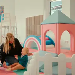 En mamma leker med sitt barn i en lekplats. En rolig och gratis upplevelse för barn i Stockholm.