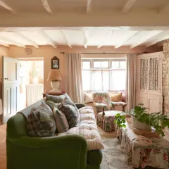 A cozy living room with a green sofa, floral armchair, and a bench, all embodying a charming modern grandma style.