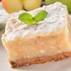 Pyszne, ekspresowe ciasto z jabłkami, posypane cukrem pudrem i udekorowane listkiem mięty. Idealne na szybki deser.