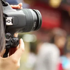 A person's hands hold a Canon digital camera, ready to capture a moment. This image is a great visual for anyone learning how to buy a digital camera.