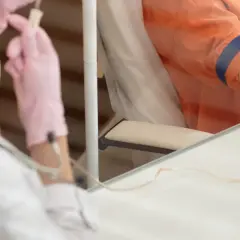 Pierwsza chemioterapia: pielęgniarka w różowych rękawiczkach przygotowuje kroplówkę dla pacjenta.