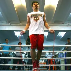 A boxer skip rope in a boxing ring, with spectators watching.