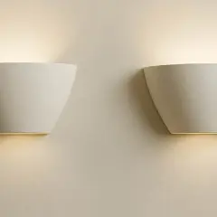 Dos elegantes flexos de pared blancos emiten una luz cálida y difusa, creando un ambiente acogedor en la estancia.