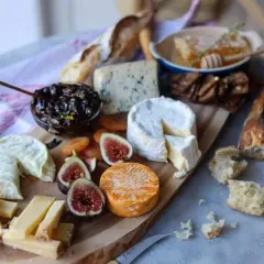 Un plateau gourmand pour explorer l'univers du fromage : brie, bleu, chèvre, pain, figues, abricots secs et miel.