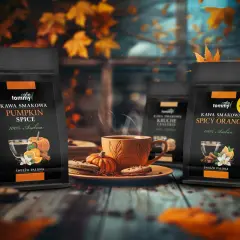 Jesienna aranżacja z kawą Tommy. Na pierwszym planie dwie paczki kawy: Pumpkin Spice i Spicy Orange. W centrum parujący kubek kawy, ciasteczka i dynie.