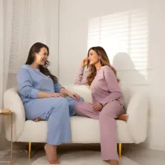 Dwie kobiety w pastelowych piżamach plus size rozmawiają na kanapie.