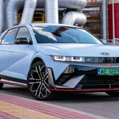 Niebieski Hyundai Ioniq 5 N z czerwonymi akcentami na tle przemysłowej infrastruktury.