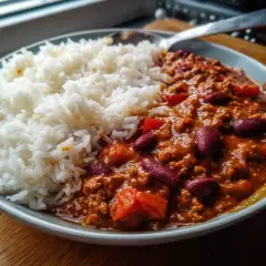En skål med fluffigt ris bredvid en mustig chili con carne med bönor och köttfärs. En perfekt middag!