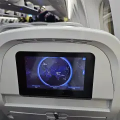 Wnętrze samolotu Neos Air. Ekran pokładowy pokazuje mapę świata z zaznaczoną trasą lotu z Wiednia do Phuket.