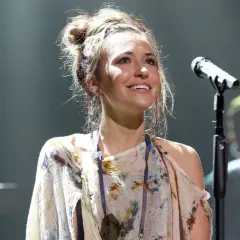 Lauren Daigle, mit hochgesteckten Haaren und einem bunten Kleid, singt auf der Bühne ins Mikrofon.