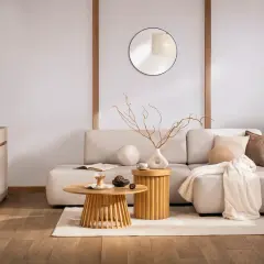 Salon w stylu zen. Jasna kanapa, drewniane stoliki, okrągłe lustro i subtelne dekoracje tworzą oazę spokoju.
