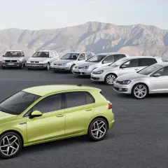 Evolución de los modelos Golf por años, desde el clásico hasta el moderno verde lima, alineados ante un paisaje montañoso.