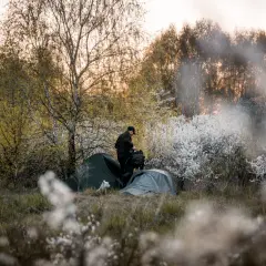 Osoba rozkłada namioty na dzikim polu. Idealne miejsce na darmowe pola namiotowe w Polsce.