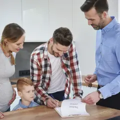 Familia firma contrato de compraventa. El agente inmobiliario les explica que es legal pedir aval para un alquiler.
