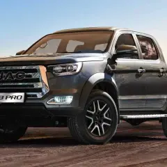 Ciemnoszary pickup JAC T8 PRO z chromowanym grillem i felgami stoi na piaszczystym podłożu.