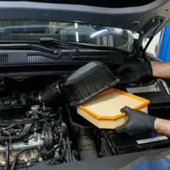 Manos enguantadas cambian el filtro del aire del coche. Este componente es vital para el motor, ya que el filtro del aire ¿para qué sirve? Limpia el aire que entra.