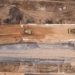 Bagger verdichten die **hydraulisch gebundene Tragschicht** auf einer Baustelle.