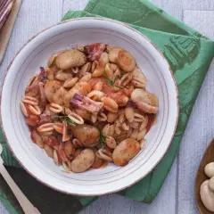 Gnocchetti alla sarda con fagioloni, pancetta y salsa de tomate, decorado con romero.