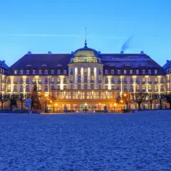 Grand Hotel w Sopocie, jeden z najpiękniejszych hoteli w Polsce, lśni nocą nad piaszczystą plażą.
