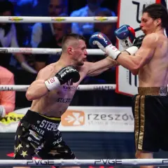 Dwóch bokserów walczy na ringu podczas babilon boxing show. Jeden z nich wyprowadza cios.