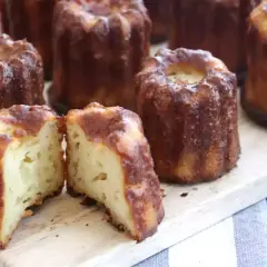 Délicieux cannelés dorés, un classique de la recette cannelés. L'un est coupé en deux, révélant sa mie moelleuse.