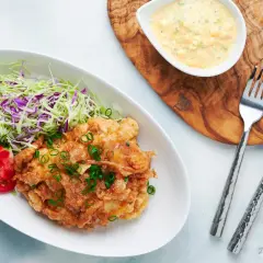 Crispy nanban food, a delicious fried chicken dish, served with shredded cabbage, tomato slices, and a creamy tartar sauce.