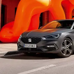 Grå Seat Leon Sportstourer parkerad framför en orange skulptur. En perfekt bil för en seat leon sportstourer test.