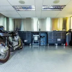 Garage per moto fai da te con moto custom, banchi da lavoro, cassettiere e attrezzi.