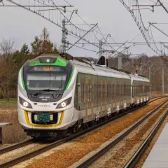 Nowoczesny pociąg 45WE-006E z zielonymi akcentami mija peron, gotowy do dalszej podróży.