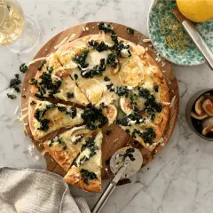 En härlig pizza med grönkål och fikon, perfekt som middagstips helg. Serveras med ett glas vitt vin och citronzest.