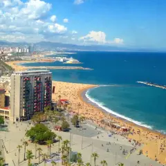 Słoneczna plaża Barceloneta tętni życiem. Tłumy ludzi odpoczywają na piasku, a błękitne morze zaprasza do kąpieli.