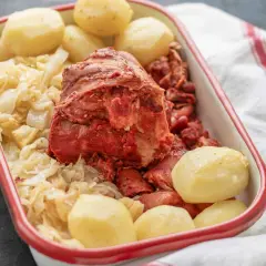 Un plato de botillo, con repollo, patatas y trozos de carne roja.