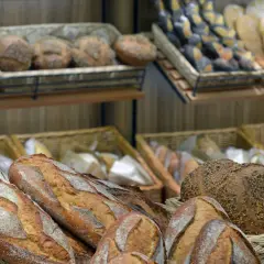 Na półkach piekarni widać różne rodzaje pieczywa. Wśród nich są bochenki z ziarnami, które mogą być odpowiedzią na pytanie, jaki chleb jest najzdrowszy.