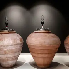 Quattro anfore in terracotta, con tappi metallici e gorgogliatori, pronte per la fermentazione del vino.