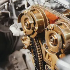 Złote koła zębate i łańcuch tworzą skomplikowany mechanizm rozrządu w aucie.