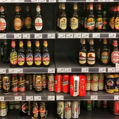 Półki sklepowe uginają się pod ciężarem piwa na półce. Butelki i puszki różnych marek tworzą kolorowy krajobraz.