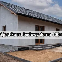 Budowa domu 100 m² – poznaj koszty. Nowy, szary dom w stanie surowym, z dachem i oknami, otoczony placem budowy.