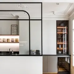 Elegante cocina semiabierta cristal con estantes iluminados, vitrina y vinoteca. Un espacio moderno y funcional.