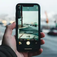 Dłoń trzyma smartfon, na ekranie którego widać zimowy krajobraz portu. Zbliżenie uchwyciło subtelny pixel shift, dodając głębi scenie.