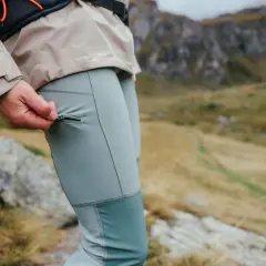 Dłoń zamyka zamek w kieszeni, pokazując jakie spodnie trekkingowe są idealne na górskie wędrówki.