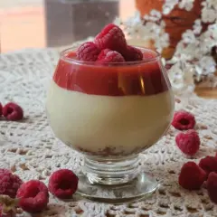 Deliciosa tarta de queso sin horno en copa, coronada con frambuesas frescas y coulis de frutos rojos.