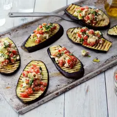 Grilla aubergine halvor toppade med en fräsch blandning av tomat, fetaost och örter. Perfekt som förrätt eller tillbehör.