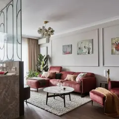 Elegancki salon z bordową kanapą i fotelem. Modne ściany w salonie zdobią obrazy, a kuchnia oddzielona jest ażurową ścianką.