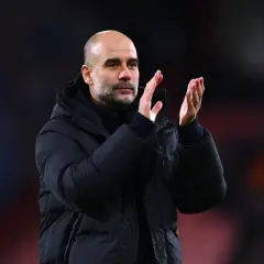 Pep Guardiola, znany z tego, że prowadzone drużyny osiągają sukcesy, klaszcze na boisku w zimowej kurtce.