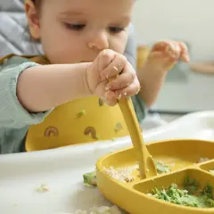 Dziecko próbuje samodzielnie jeść, chwytając widelczyk. Zastanawiasz się, ile razy w tygodniu mięso dla niemowlaka?