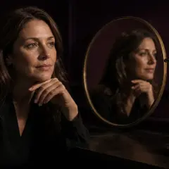 En kvinna betraktar sin spegelbild bredvid ett timglas. Kanske funderar hon på botox effekt tid.