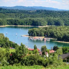 Piękna pogoda w Bieszczadach, nad Soliną w Polańczyku. Jezioro pełne żaglówek, otoczone zielonymi lasami i domkami.
