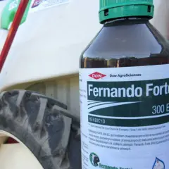 Butelka herbicydu Fernando Forte 300 EC na tle traktora.