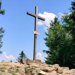 Drewniany krzyż na skalistym szczycie, otoczony zielenią. Idealne miejsce, by odkryć, co zobaczyć w Górach Świętokrzyskich.